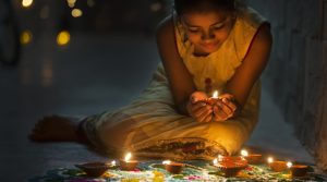 Girl making Rangoli and decorating with Oil lamps for Diwali