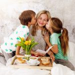 Mother´s Day – two children surprise their mother with breakfast in modern bed