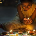 Girl making Rangoli and decorating with Oil lamps for Diwali